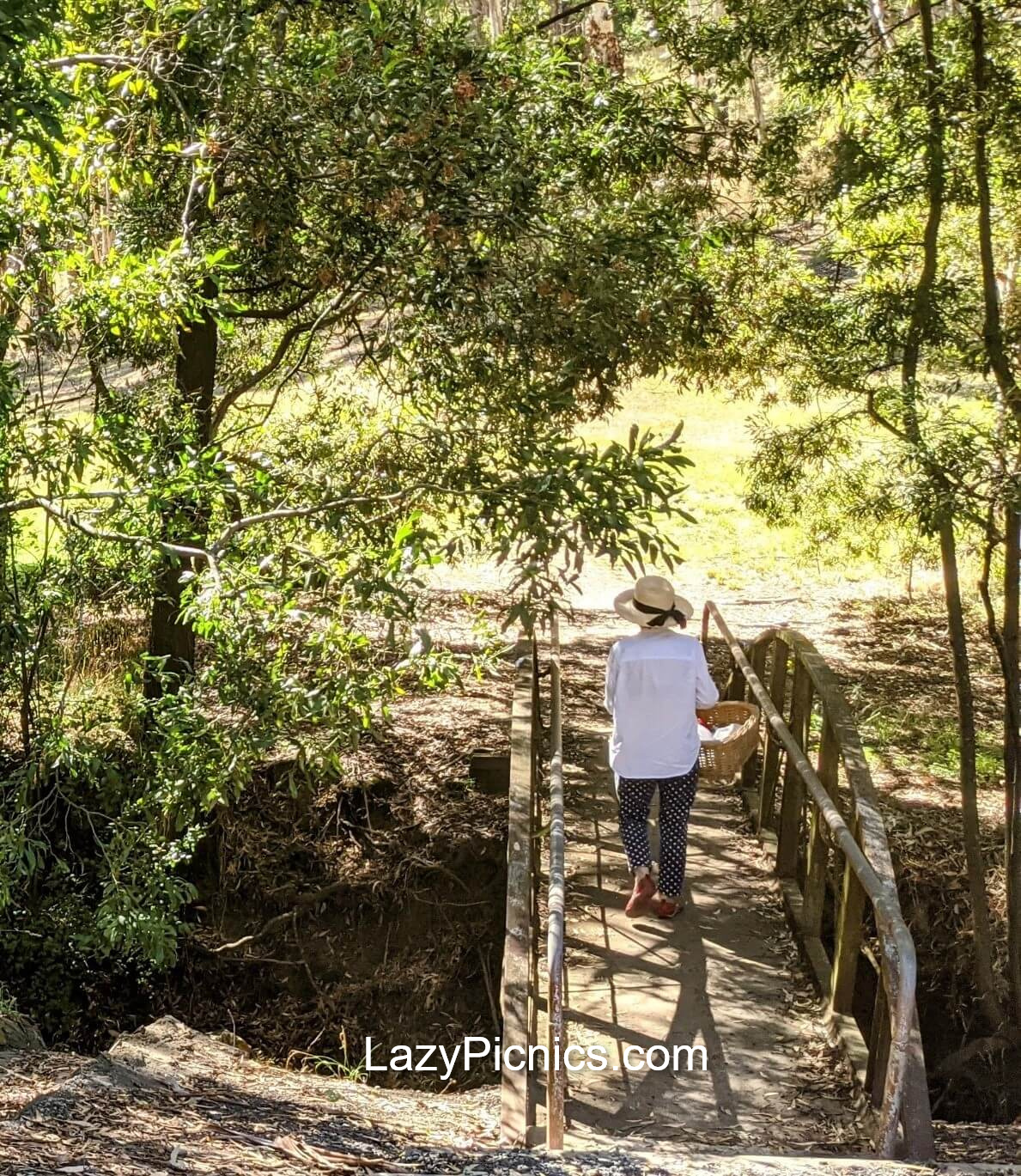 Lady crossing a bridge with her picnic basket.
